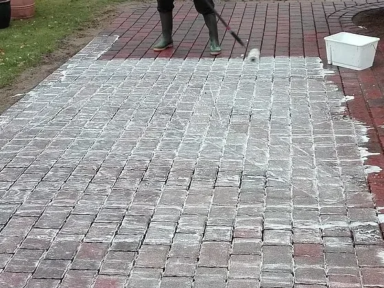 Nakładanie środka przeciwko chwastom i mchu na kostkę brukową.